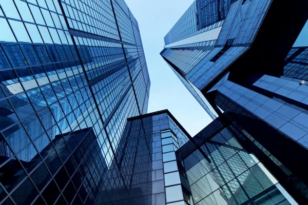 Modern professional office building exterior, glass windows, under a clear blue sky. low angle skyscrapers view